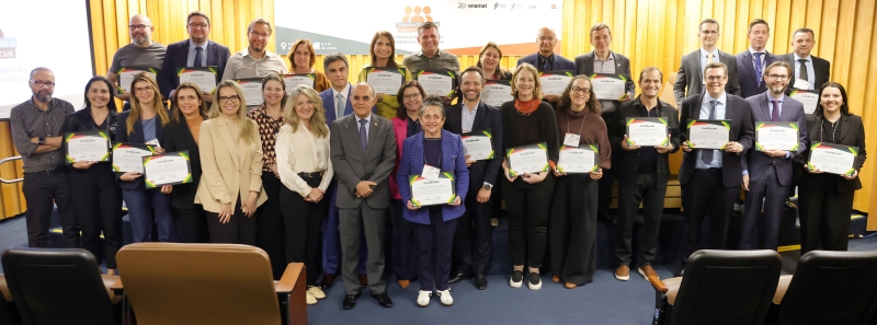Dezenas de juízes e juízas em pé lado a lado segurando certificados