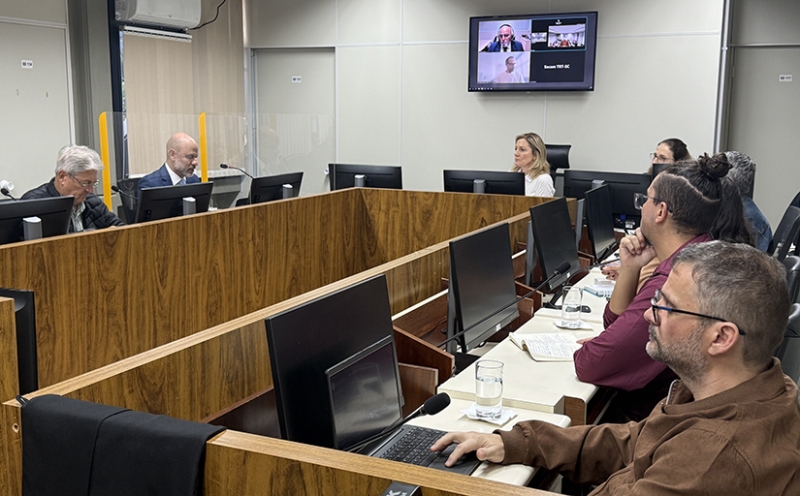 Homens e mulheres sentados ao redor de uma mesa em formato de U