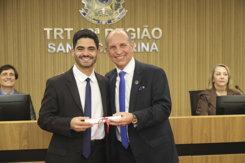 dois homens de terno preto segurando um diploma