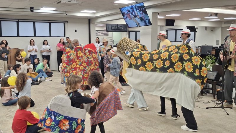 Apresentação cultural com crianças e adultos em uma dança de boi de mamão, acompanhada por músicos e instrumentos.