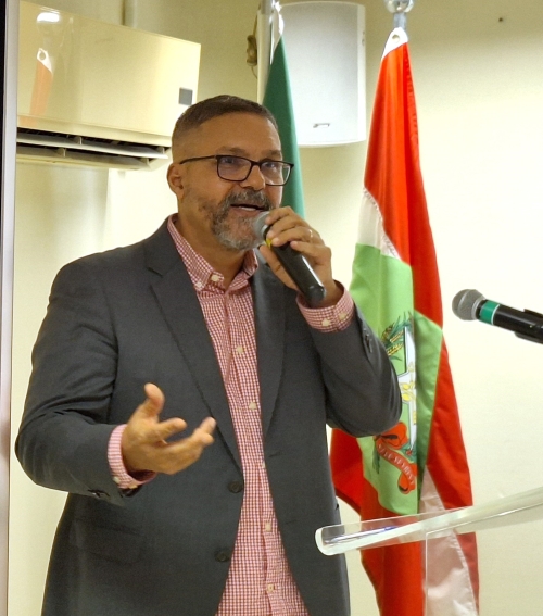 homem de pé gesticula enquanto fala ao microfone para a plateia