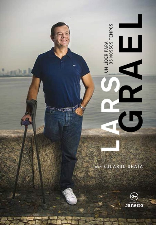 Para todos verem: Texto: “Lars Grael. Um líder para os nossos tempos. Com Eduardo Ohata. Edições de Janeiro”. Ilustração: Capa do livro em que há a foto de um homem com deficiência física sorrindo. Ao fundo há o mar.