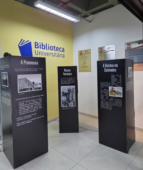 Três biombos decorados com fotos em preto e branco e textos sobre trabalho escravo contemporâneo