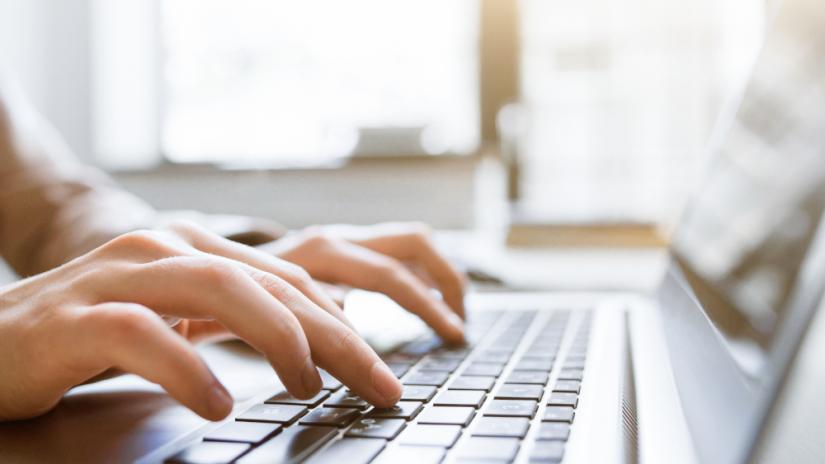 Mãos digitando em um teclado de notebook