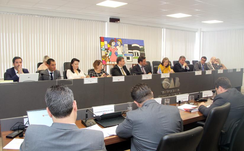 Foto da reunião do Conselho Pleno da OAB-SC, com a presidente Lourdes Leiria à mesa falando ao microfone 