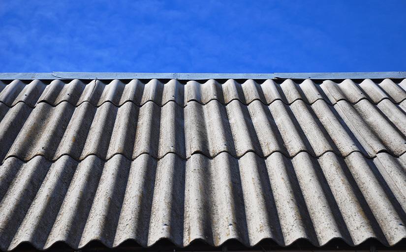 Foto de um telhado com telas cinzas; ao fundo, céu azul