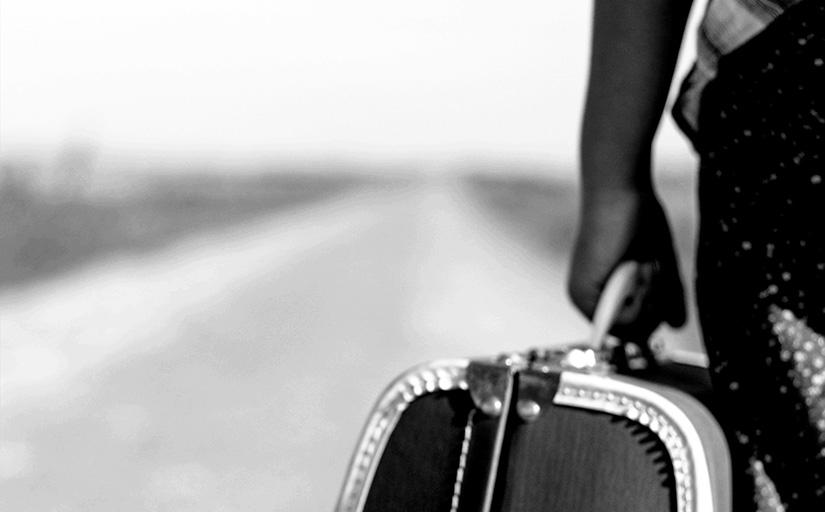 foto de um homem diante de uma estrada com uma maleta na mão