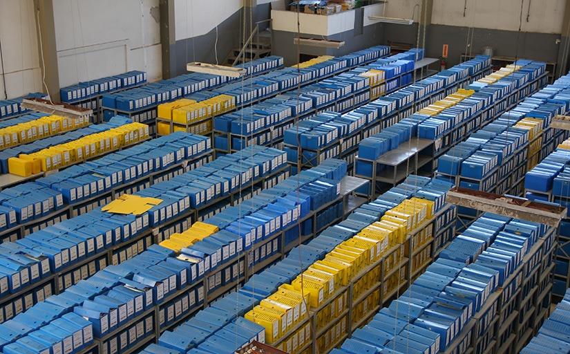 foto superior de centenas de caixas de arquivo azuis e amarelas em um galpão