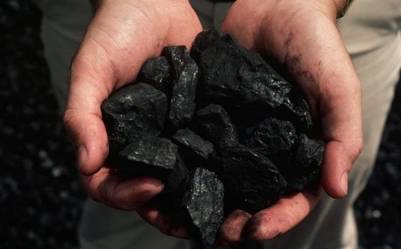 Duas mãos em forma de concha mostram um punhado de carvão