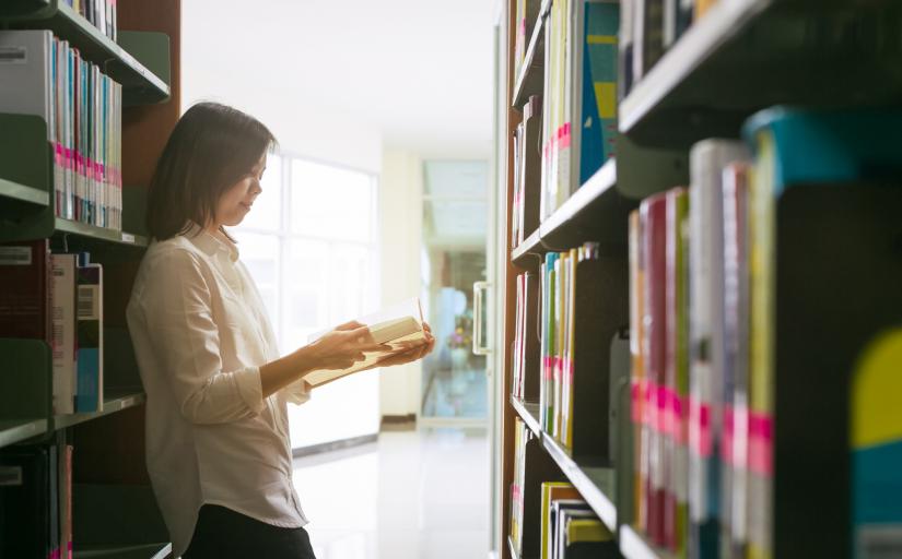 Estudante lendo um livro na biblioteca.