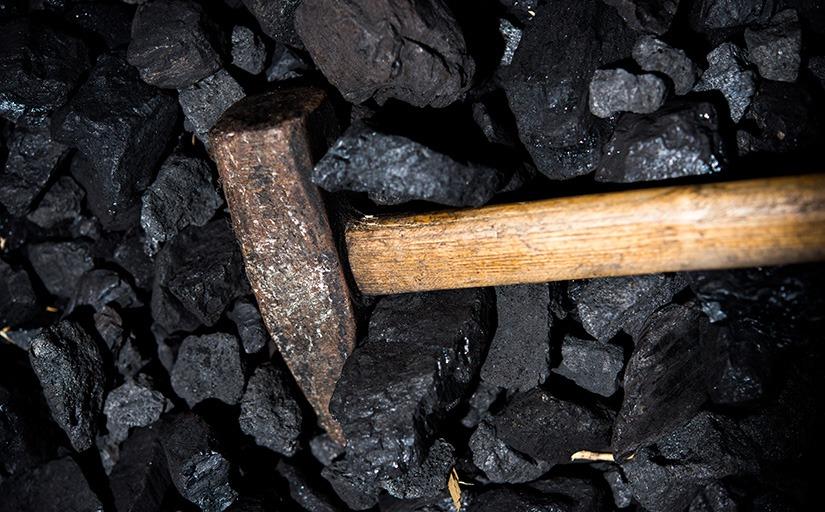 fotografia ilustrativa de um martelo de mineração em cima de pedras de carvão