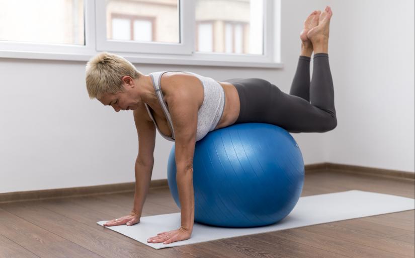 Mulher sênior faz exercício sobre uma bola de pilates