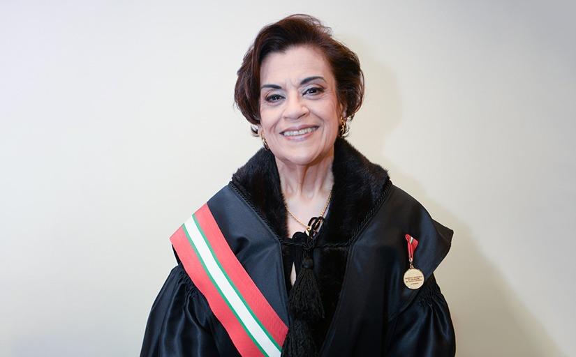 Desembargadora Ligia Maria Teixeira Gouvêa, sorrindo, com toga e faixa nas cores vermelha, branca e verde