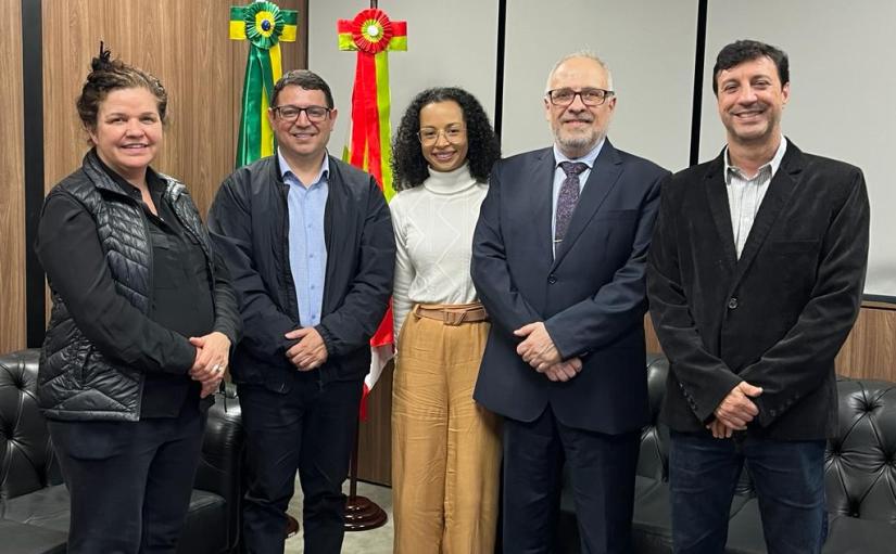 Três homens e duas mulheres em pé e sorridentes posam para a foto