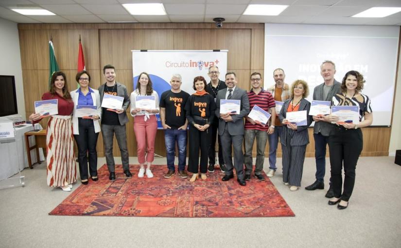 fotografia com várias pessoas, em pé, segurando certificados e sorrindo para a câmera