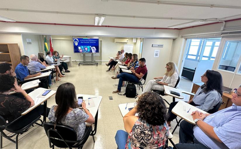 fotografia da sala em que aconteceu a reunião, homens e mulheres dispostos em cadeiras de frente para uma tela de apresentação