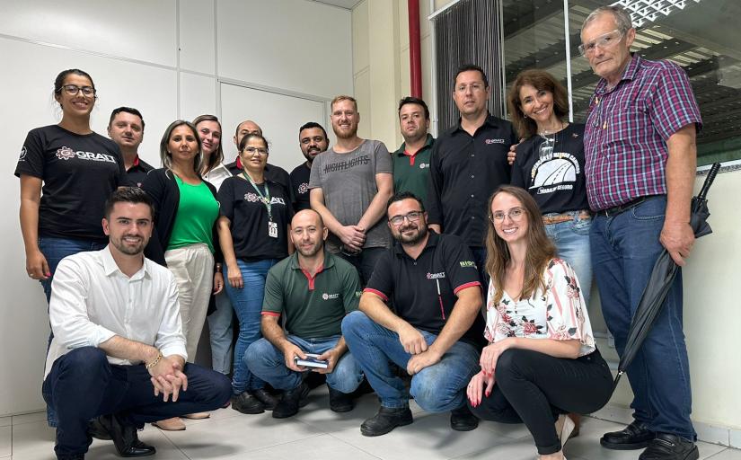 Fotografia de um grupo de homens e mulheres sorrindo para a câmera em um ambiente de trabalho