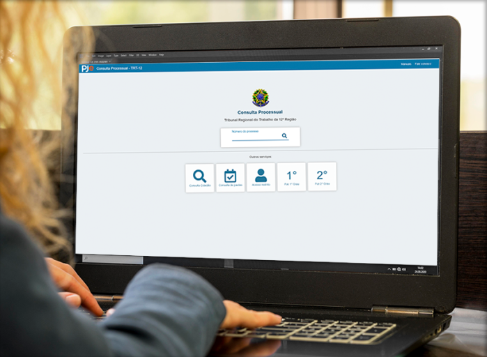 Pessoa está em frente a uma tela de computador com a página do Processo Judicial Eeltrônico aberta