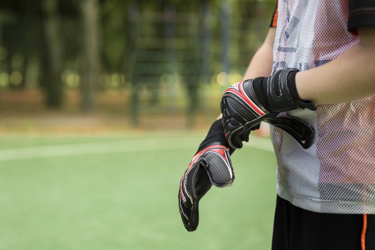 Um goleiro de futebol veste luva em uma das mãos