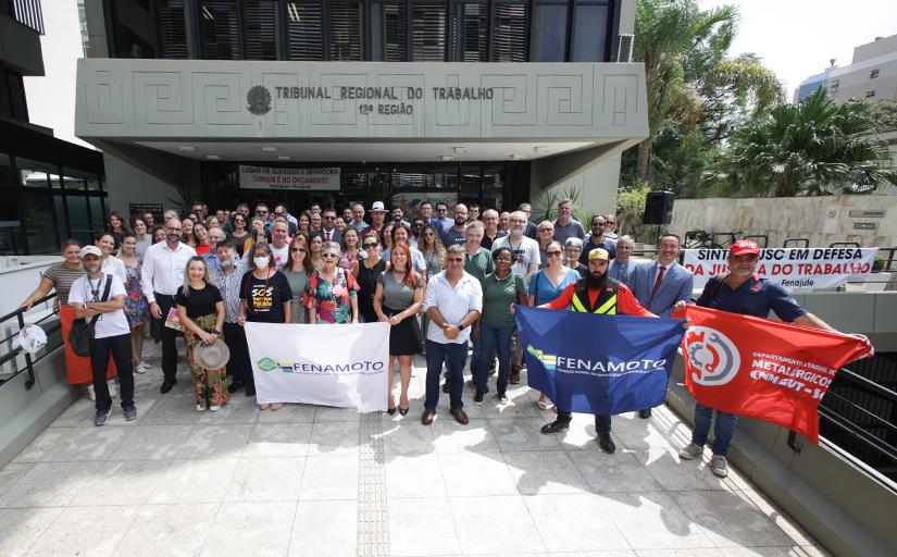 Um grupo de cerca de 100 pessoas aglomeradas posam em uma rampa inclinada, na entrada do prédio-sede do Tribunal Regional do Trabalho de Santa Catarina