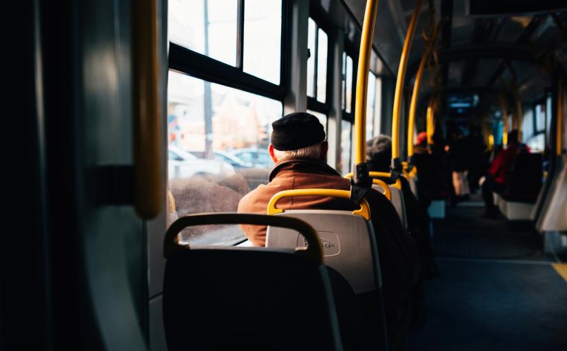 interior de um ônibus com um homem de touca preta sentado de costas