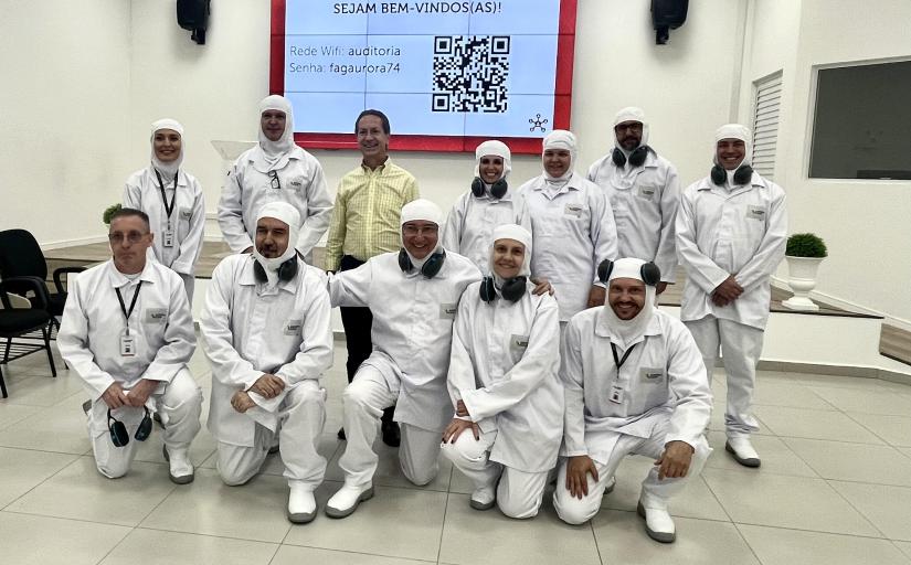 Foto de um grupo de pessoas trajando uniformes de trabalho utilizados em frigoríficos.