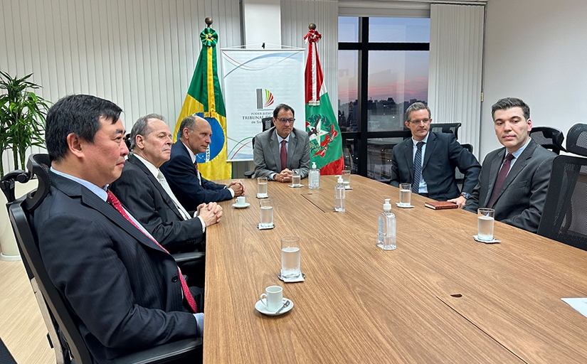 Fotografia traz seis homens, em trajes formais, sentados em uma mesa longa. Ao fundo, as bandeira do Brasil e do Estado de Santa Catarina e um banner com a identidade visual do Tribunal de Justiça de Santa Catarina.