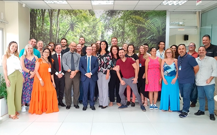 Fotografia de um grupo de trinta pessoas em pé sorrindo para a foto.