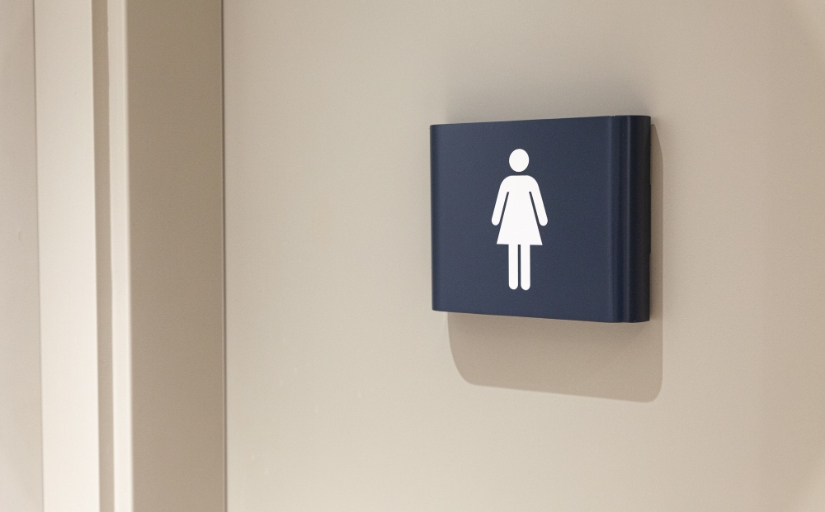 Fotografia ilustrativa de um símbolo escuro de feminino afixado à uma porta clara