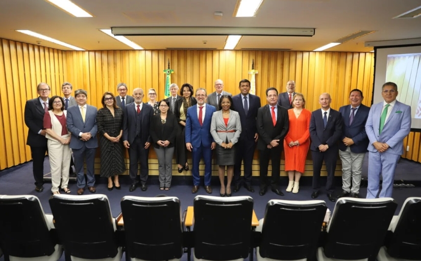 Grupo de pessoas em pé, posando para a foto, em frente a uma bancada