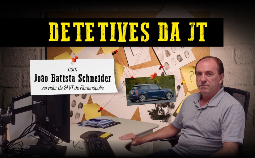 Detetives da JT: João Batista Schneider, servidor da 2ª VT de Florianópolis. Um homem branco sentando à mesa de trabalho, vestindo camisa polo cinza e olhando para a câmera