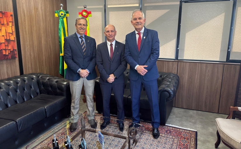 Três homens de terno e gravata estão em pé posando para a foto
