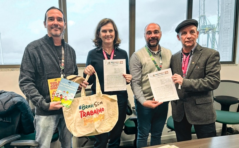 Quatro representantes posam com cartilhas e sacola da campanha Brasil Sem Trabalho Infantil após assinatura de parceria.