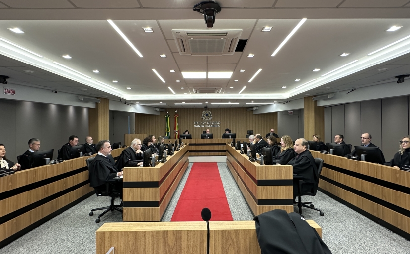 Foto de uma sala de sessões de julgamento composta por magistrados e magistradas de toga