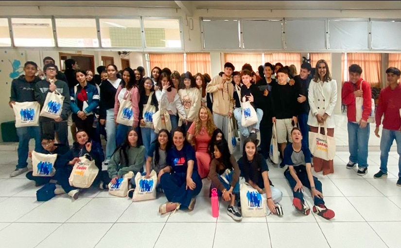 Mais de 40 jovens e três mulheres adultas estão sorrindo e posando para a foto