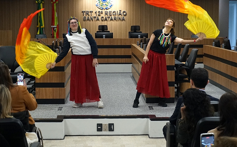 Duas jovens dançando com vestido vinho e lenços vermelhos e amarelos
