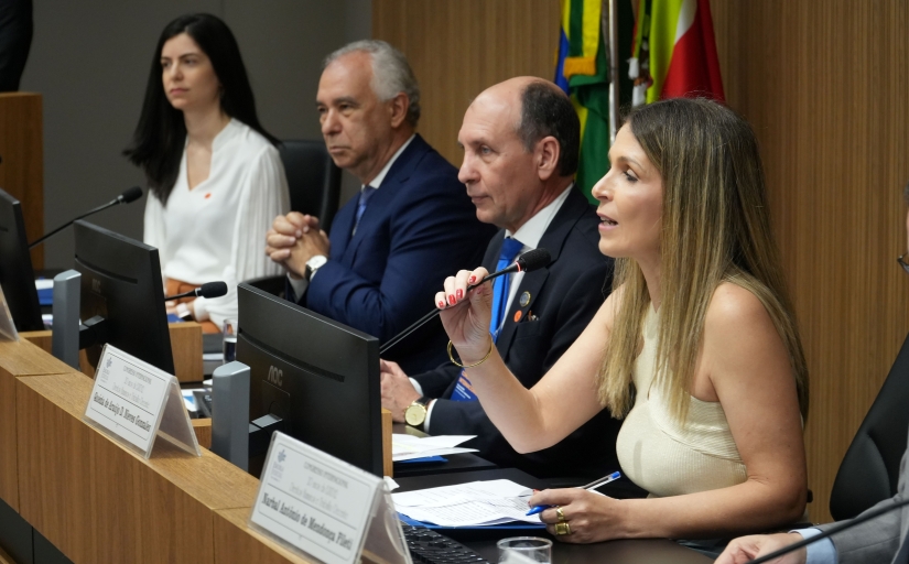 Grupo de quatro pessoas sentadas em uma bancada, como em uma mesa de abertura de evento