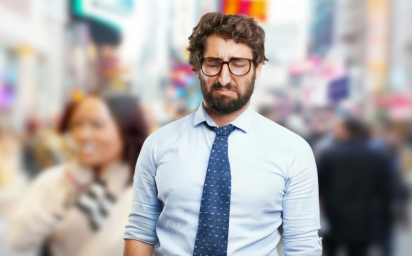 Fotografia ilustrativa de homem jovem em primeiro plano, com expressão chateada