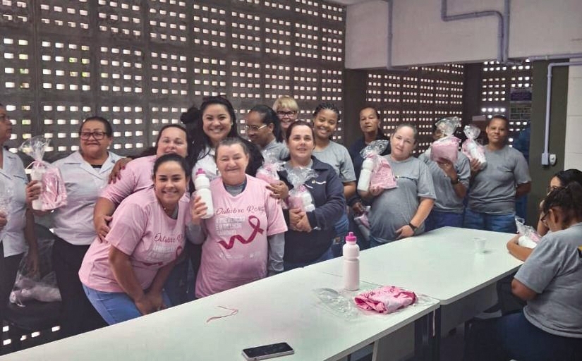 Grupo de mulheres posam para a foto. Algumas delas usam camisetas rosas do Outubro Rosa. 