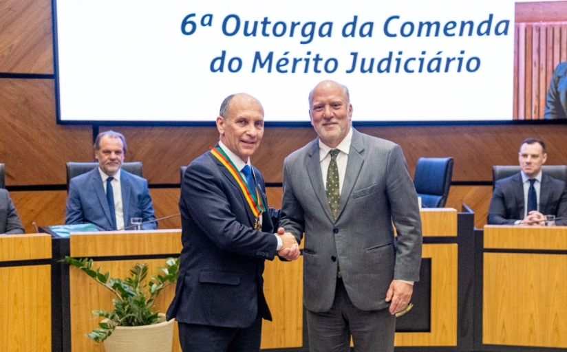 Dois homens de terno se cumprimentam e posam para foto. 