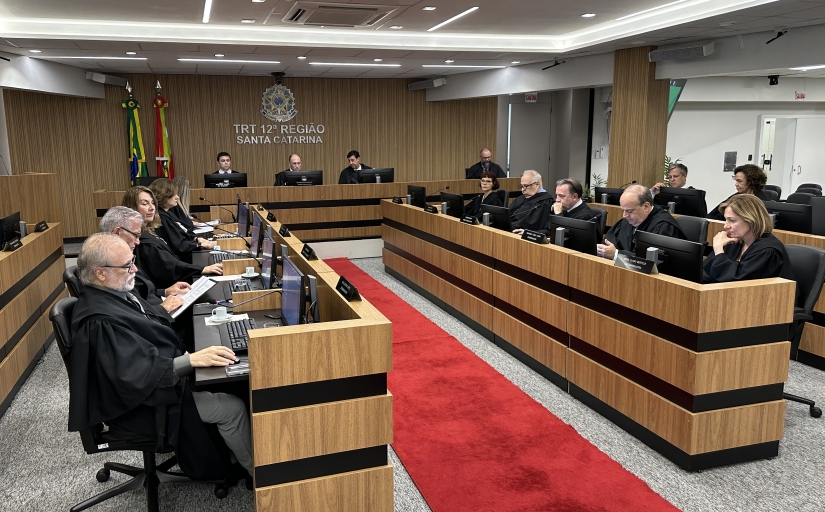 Sala de sessões de um tribunal mostrando 19 pessoas sentadas em uma mesa em formato de U