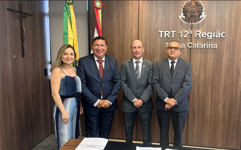 Uma mulher e três homens estão em pé, posando para a foto