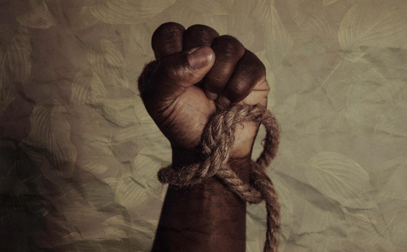 Foto da mão de um negro segurando uma corda