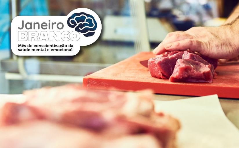 Foto mostra duas bandejas com carne sendo manipulada pelas mãos de um açougueiro. No canto superior esquerdo, o texto Janeiro Branco, mês da conscientização da saúde mental