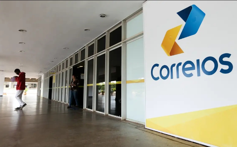 Fotografia da entrada de agência dos Correios com logo grande à direita