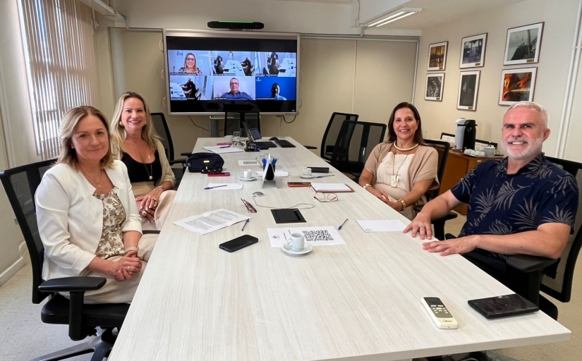 Grupo de pessoas sentadas ao redor de uma mesa branca posam para a foto