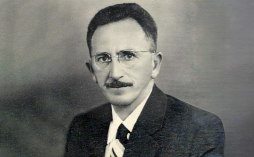 Foto preta e branca de um homem de óculos e bigode