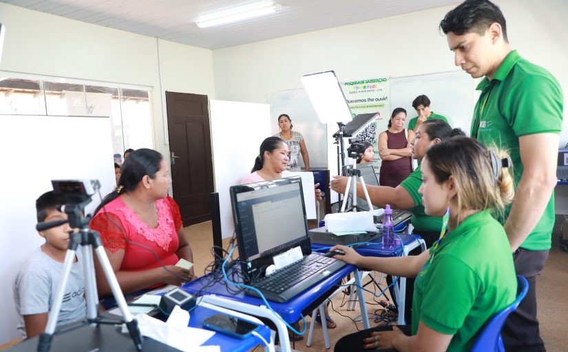 Pessoas participam de um atendimento em uma sala equipada com computadores, câmeras e outros equipamentos tecnológicos.