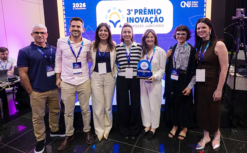 Dois homens e cinco mulher posam para foto segurando premiação