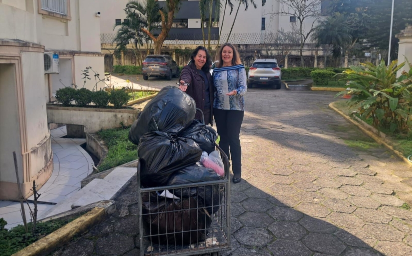 Duas mulheres sorriem para a foto diante de um carrinho cheio de doações